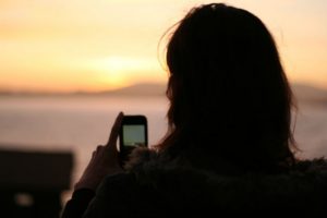 girl at sunset using app to repel mosquitoes